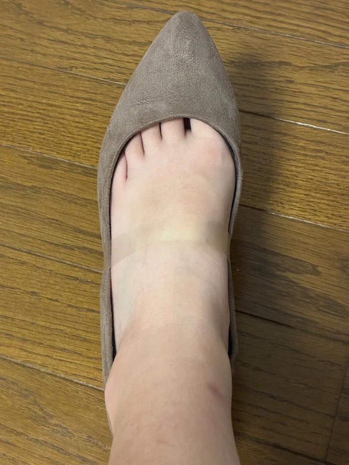 グレージュのパンプスを履いた足の甲に透明パンプスバンドを装着した様子を真上から撮影