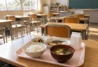 小学校の教室の机に置かれた給食のトレイ