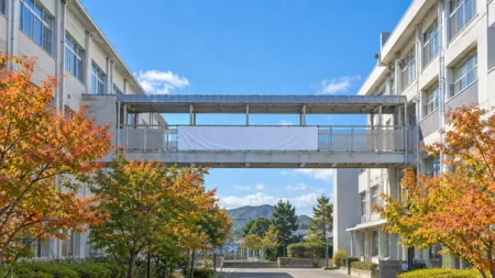 秋晴れの空の下に建つ学校の校舎と渡り廊下