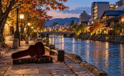 秋の夕方、都市を流れる川沿いの遊歩道に開いて置かれたアコースティックギターのケース