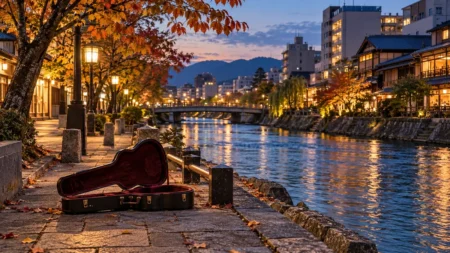 秋の夕方、都市を流れる川沿いの遊歩道に開いて置かれたアコースティックギターのケース