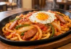 鉄板皿に盛ったナポリタン風のうどんと目玉焼きのイメージ