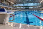 照明に照らされた屋内プールの水面とスタート台、コースロープ