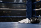 試合後の照明に照らされたボクシングリングのコーナーに置かれた白いタオルと黒いグローブ