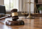 木製の机に置かれた裁判の木槌と、背景にぼかした天秤