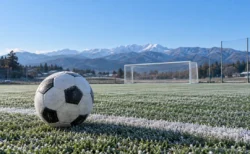 冬の高校のサッカーグラウンド、ゴール前に置かれたサッカーボールと遠くの雪をかぶった山並み