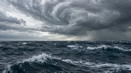 厚い雨雲が渦を巻く空の下、うねりで白波が立つ荒れた外洋