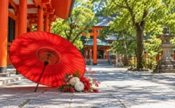 神社の境内に置かれた赤い和傘と紅白の花