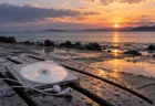 雨上がりの夕方の海辺に置かれたCDとワイヤレスイヤホン