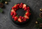 黒いクリームのホールケーキに赤いラズベリーといちごがのった、暗い背景のテーブル