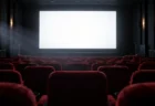 スクリーンの光に照らされた無人の映画館の客席