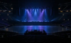 開演前の照明が落ちた無人の大型コンサートアリーナとステージのスポットライト