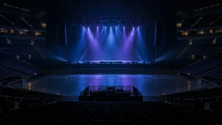 開演前の照明が落ちた無人の大型コンサートアリーナとステージのスポットライト